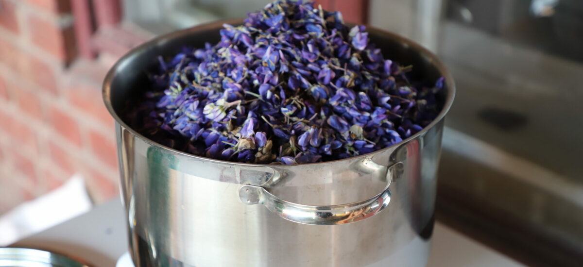 Teräskattila jossa violetin värisiä kukkia.
